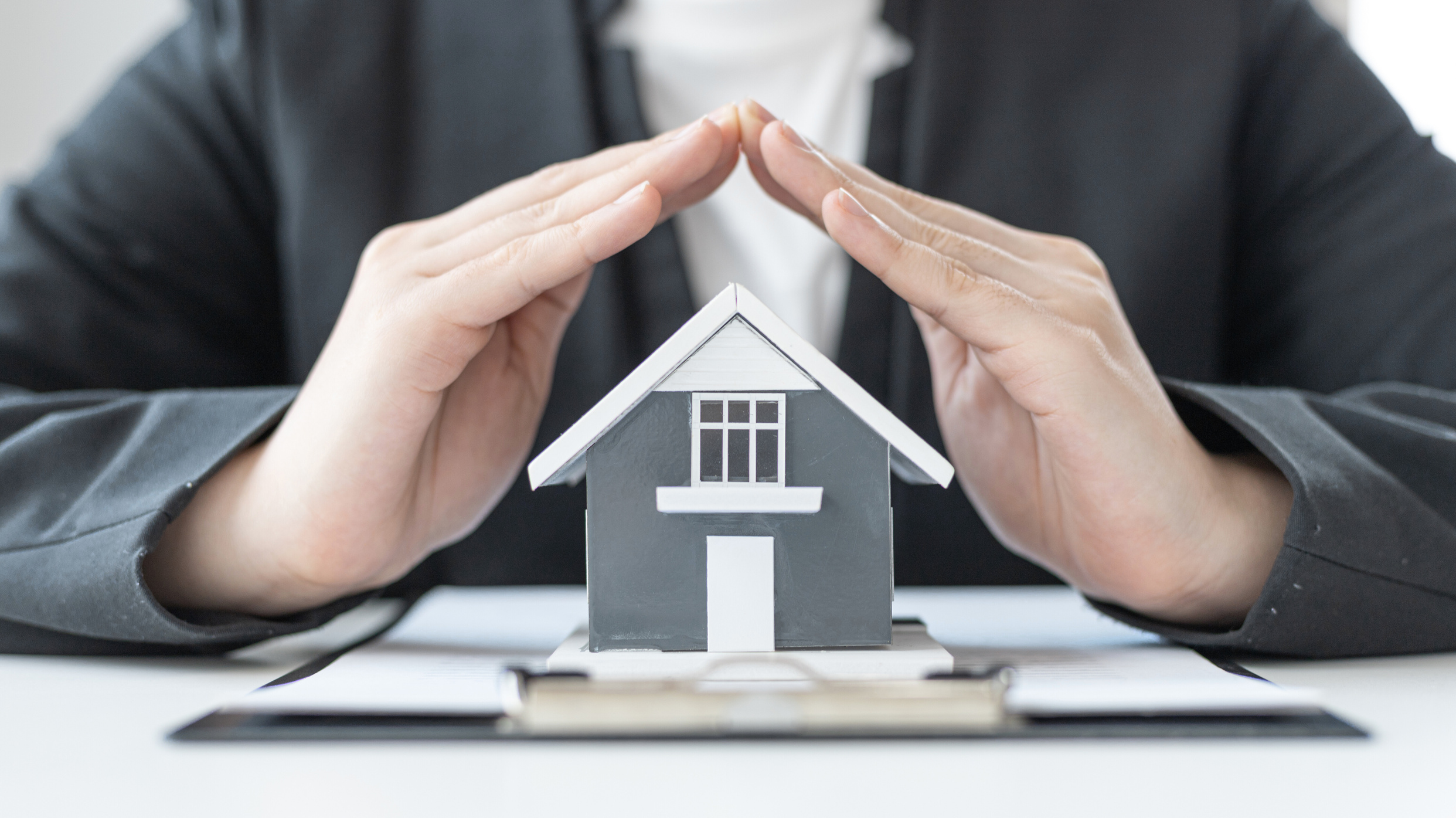 Hands protecting a model house